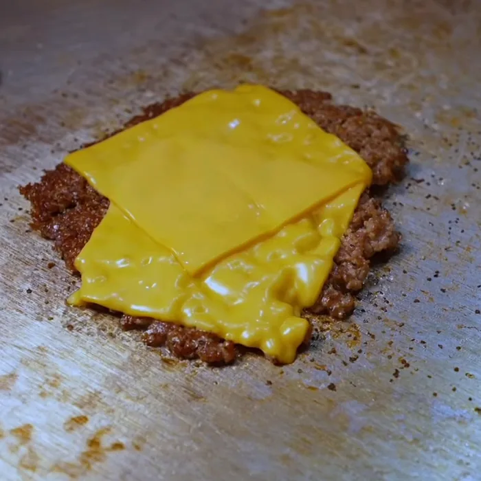 Käse schmilzt auf dem Patty auf der Grillplatte