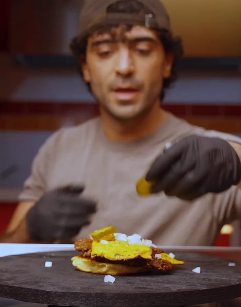 Koch bei Yummy's gibt Zwiebeln auf den Burger